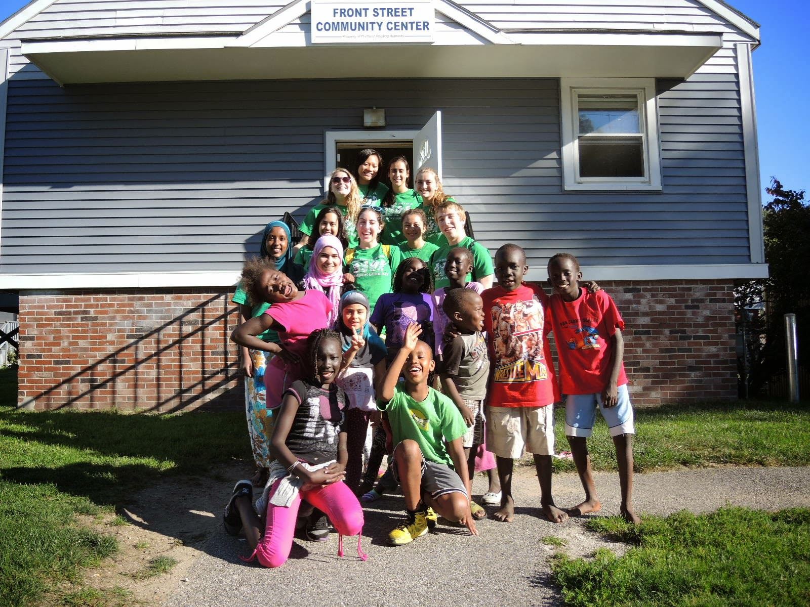 Youth from Front Street pose with volunteers in front of the Community Building